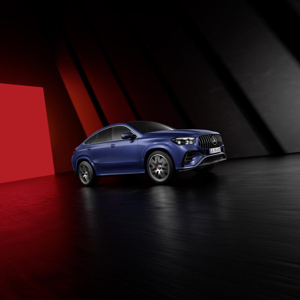 A blue Mercedes-AMG GLE Coupé in a dark studio with red and black panels