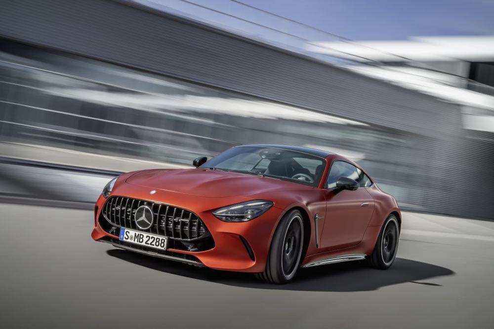 An orange matt Mercedes-AMG GT Coupé driving past a blurred building