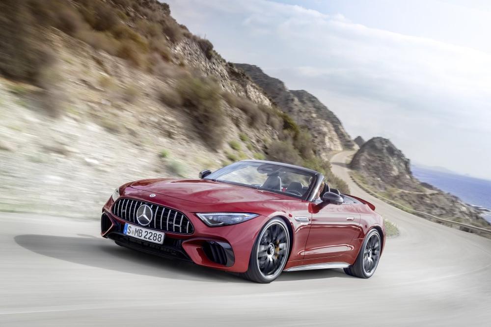 A red Mercedes-AMG SL Roadster with its roof open, driving along a winding cliff road above the sea