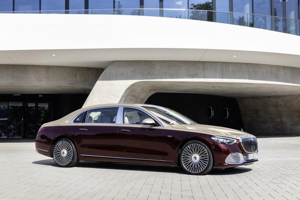 A burgundy and gold two-tone Mercedes-Maybach S-Class parked in front of a white curved building