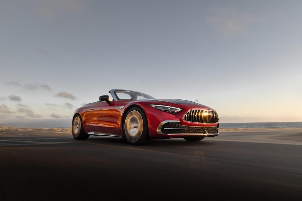 A red Mercedes-Maybach SL Monogram Series roadster with a vertical-slat grille, driving along the coast at sunset